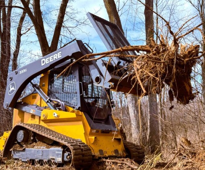 John Deere skid steer with a tree puller lifting a tree and roots on a North Texas job